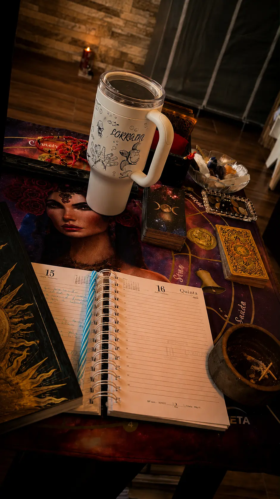 Mesa com agenda aberta, caneca, cartas e elementos espirituais